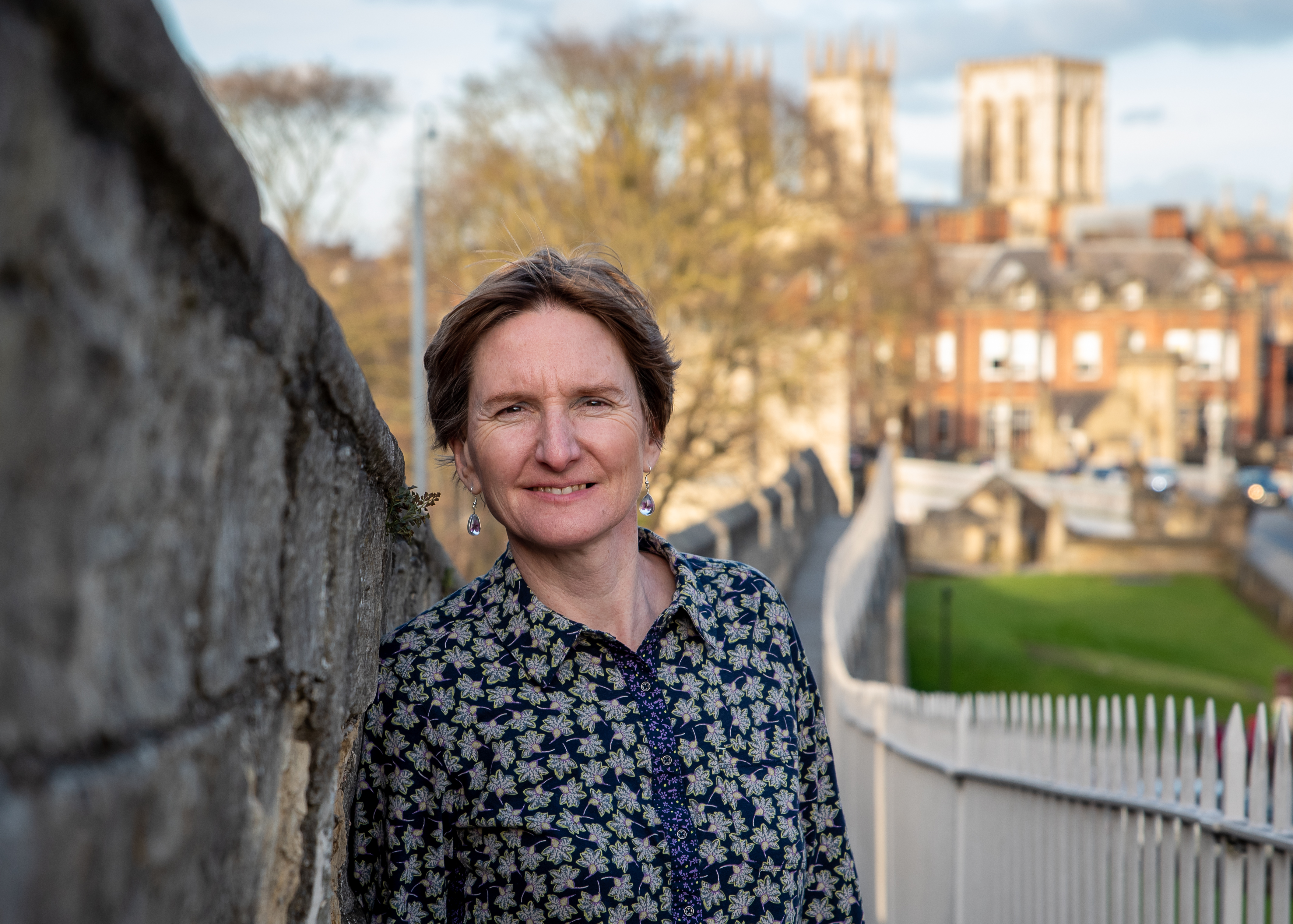 Rachel smiling at the camera, York city walls and York Minster in the background