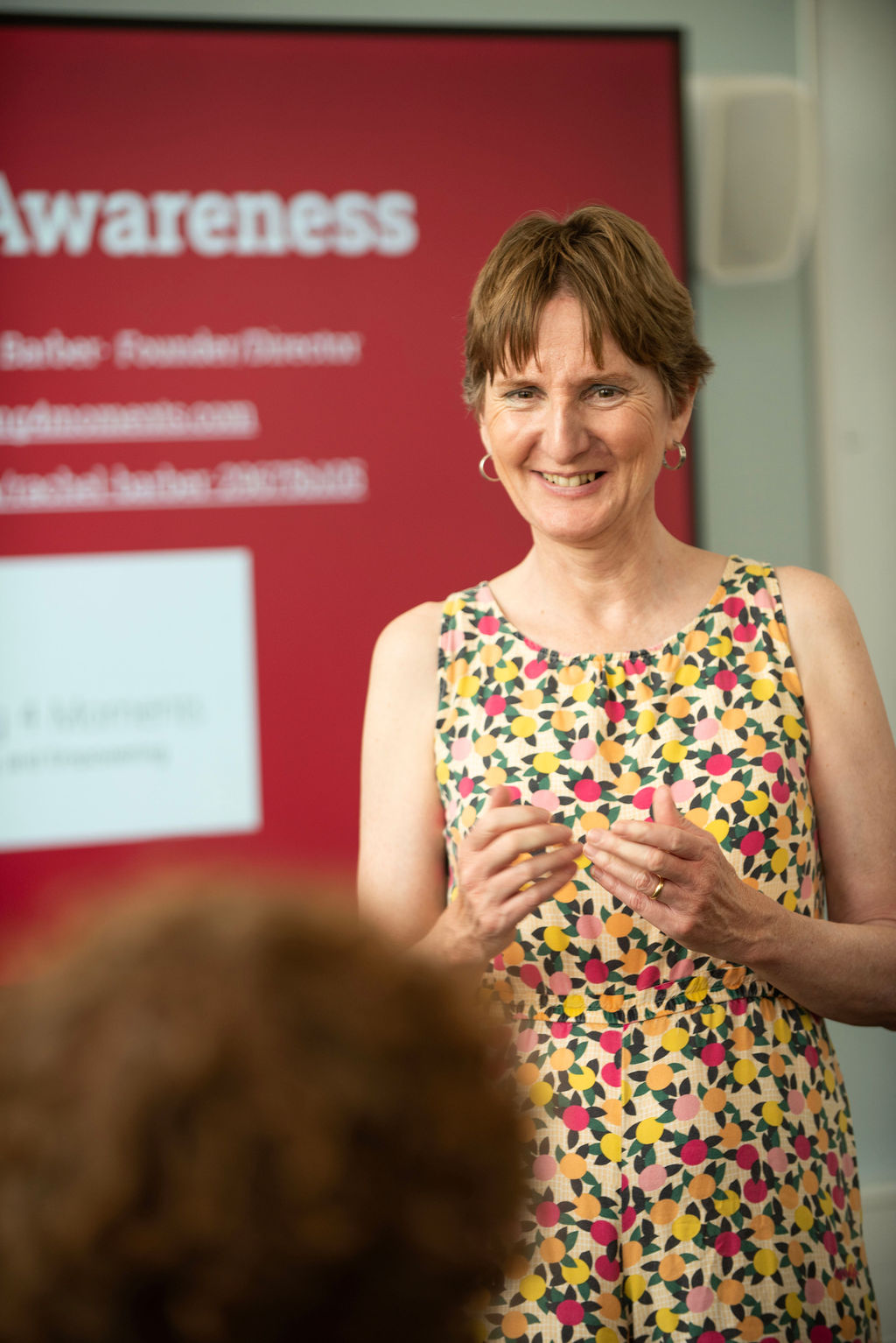 Rachel standing at the front of a class, looking towards another person.