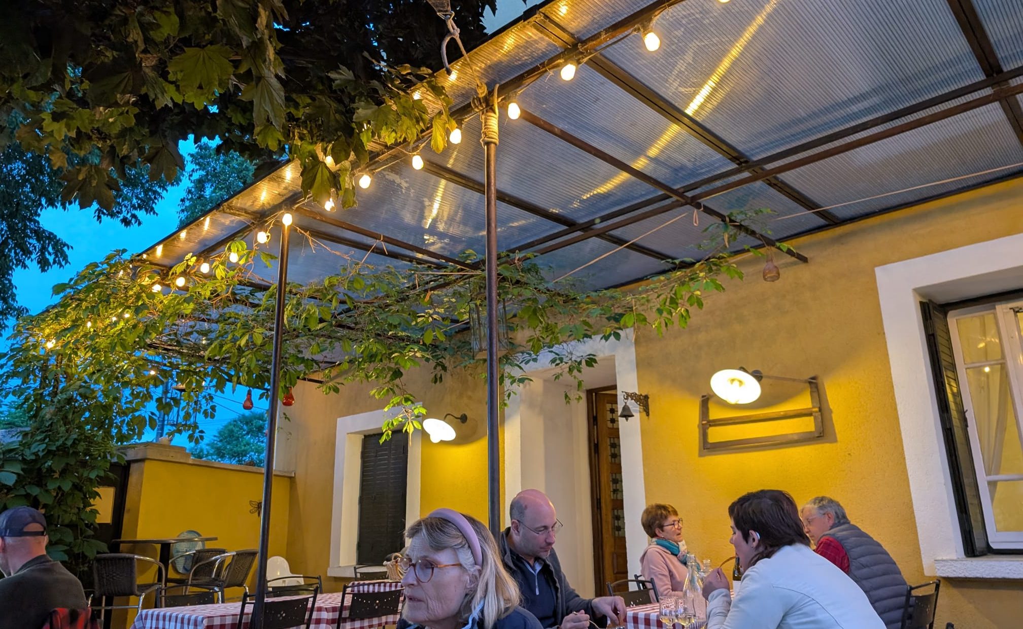 People dining together at an outdoor restaurant in the evening, managing hearing loss in noisy environments